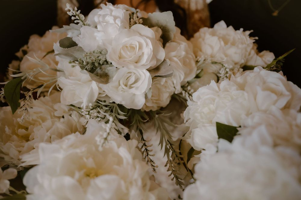 Elegant white rose bouquet with delicate greenery arranged in a romantic wedding style.