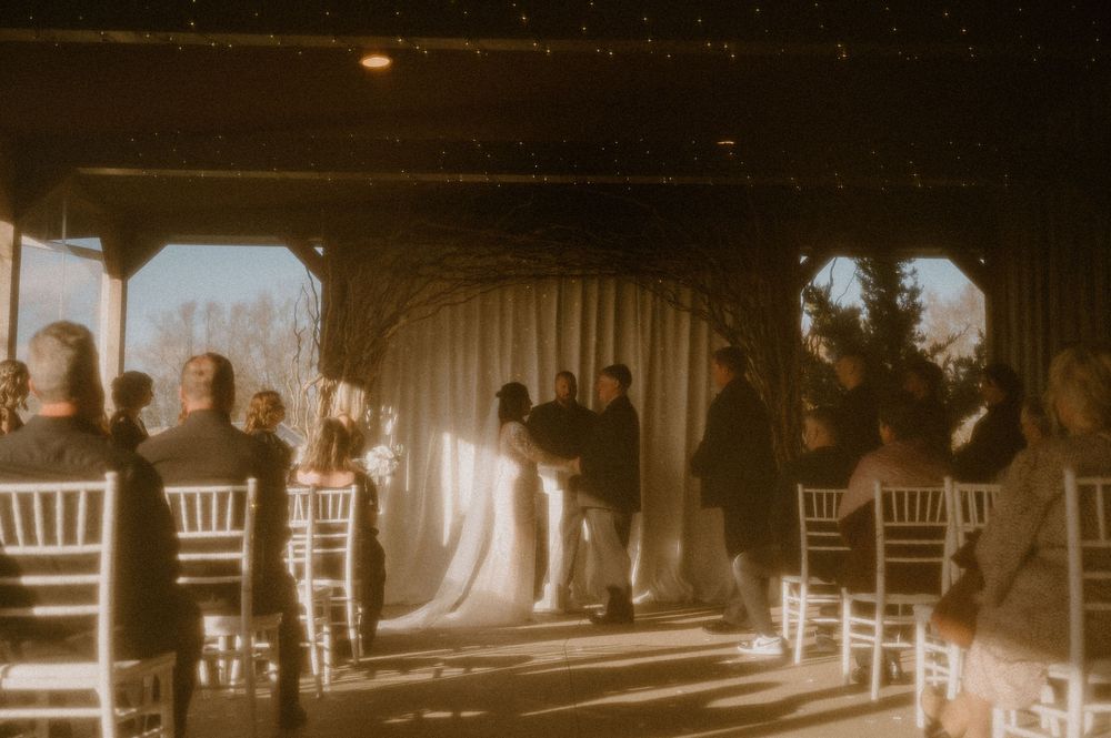 A vintage sepia-toned panoramic photograph shows a train station platform with passengers waiting in the early 1900s.