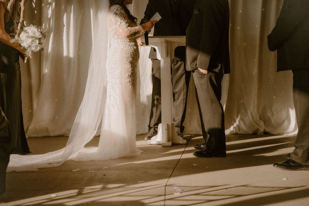Sepia-toned wedding photograph showing dress details and formal shoes in dramatic lighting and shadows.