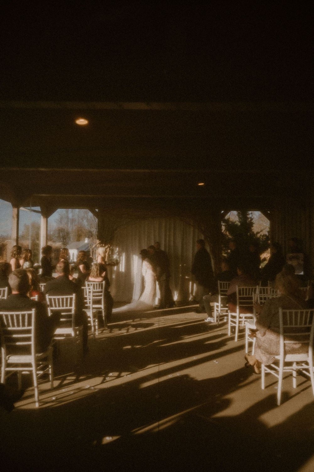 Dramatic shadows cast by white chairs in a dimly lit venue create an atmospheric pattern across the floor.