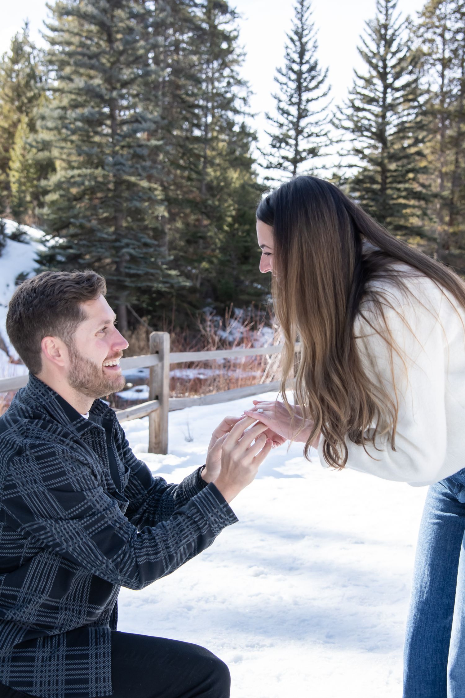 A candid moment putting on engagement ring during a winter proposal in Vail Colorado with a cute and stylish couple.