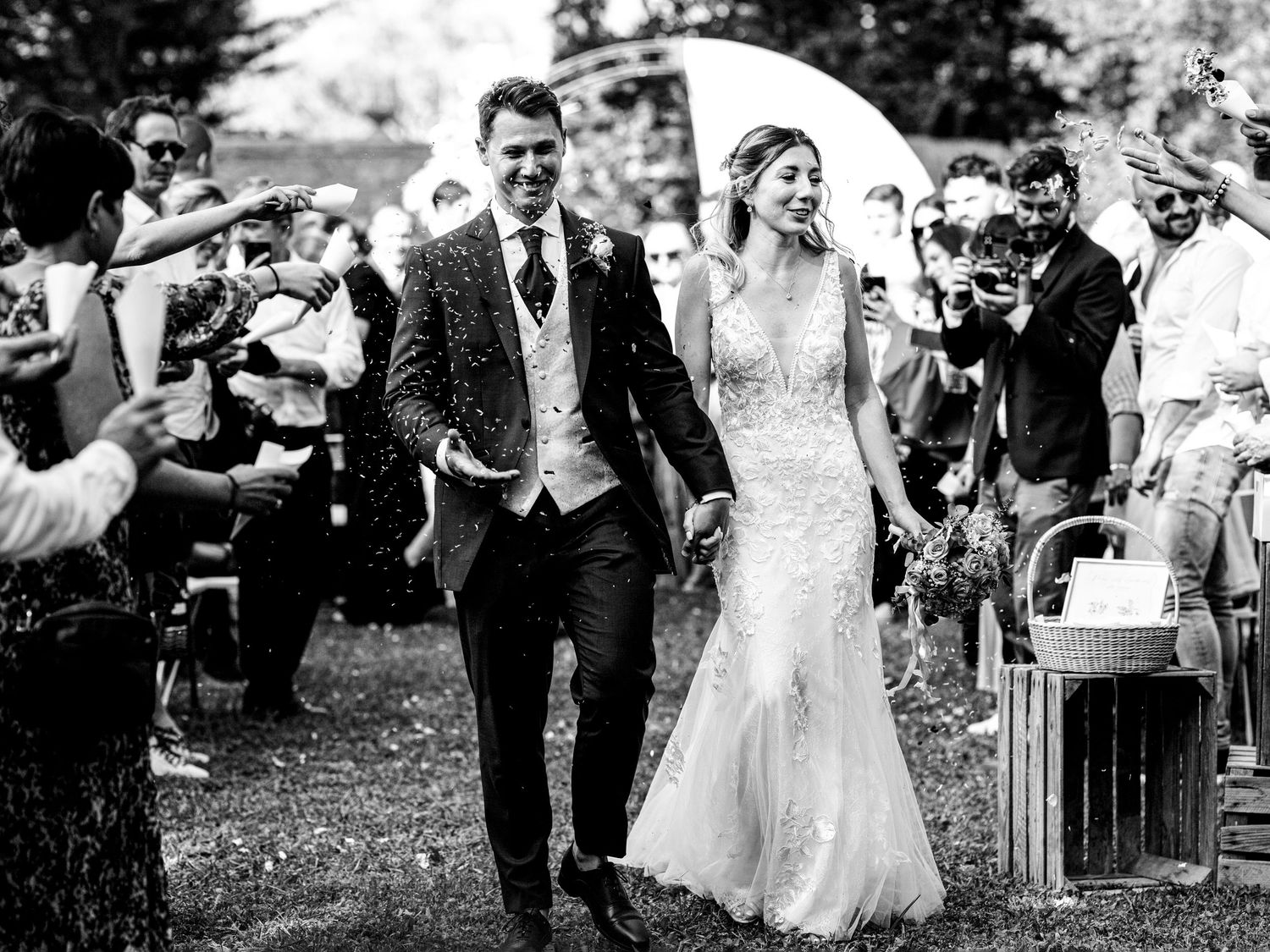 Wedding guests celebrate by blowing bubbles as the newlyweds walk down the aisle at an outdoor ceremony.