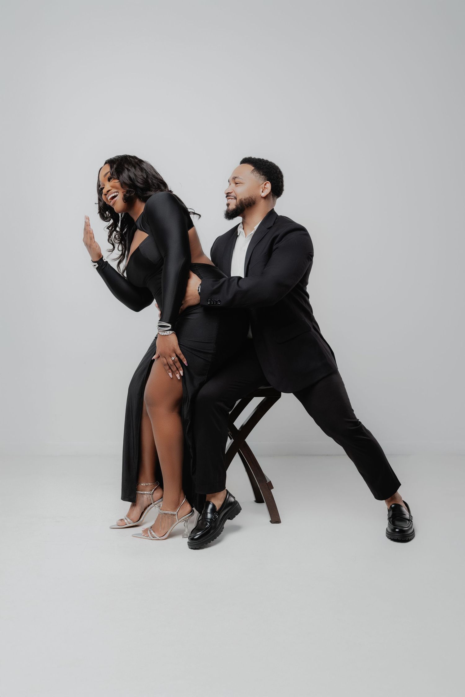 Two performers in black outfits strike dynamic poses together against a white studio backdrop in a series of photos.