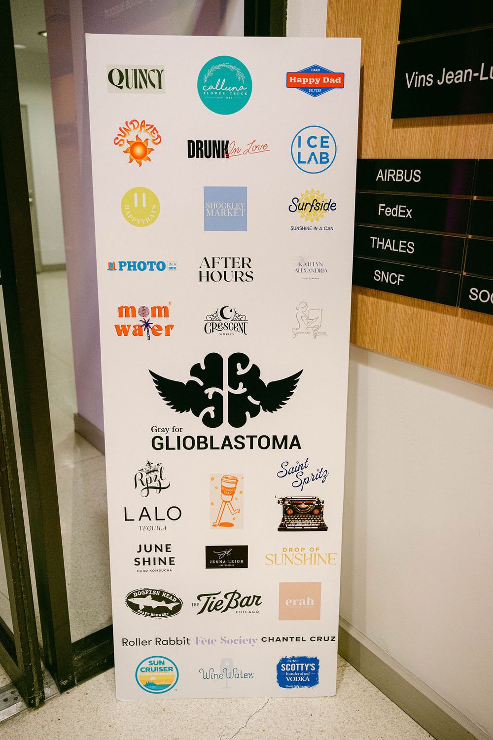 A wall display featuring various company logos and brand stickers arranged on a white surface.
