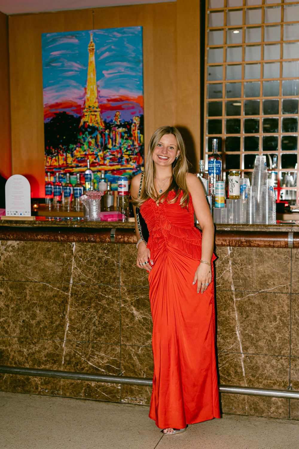 Red dresses displayed in a bar or restaurant setting with colorful cityscape artwork on the walls.