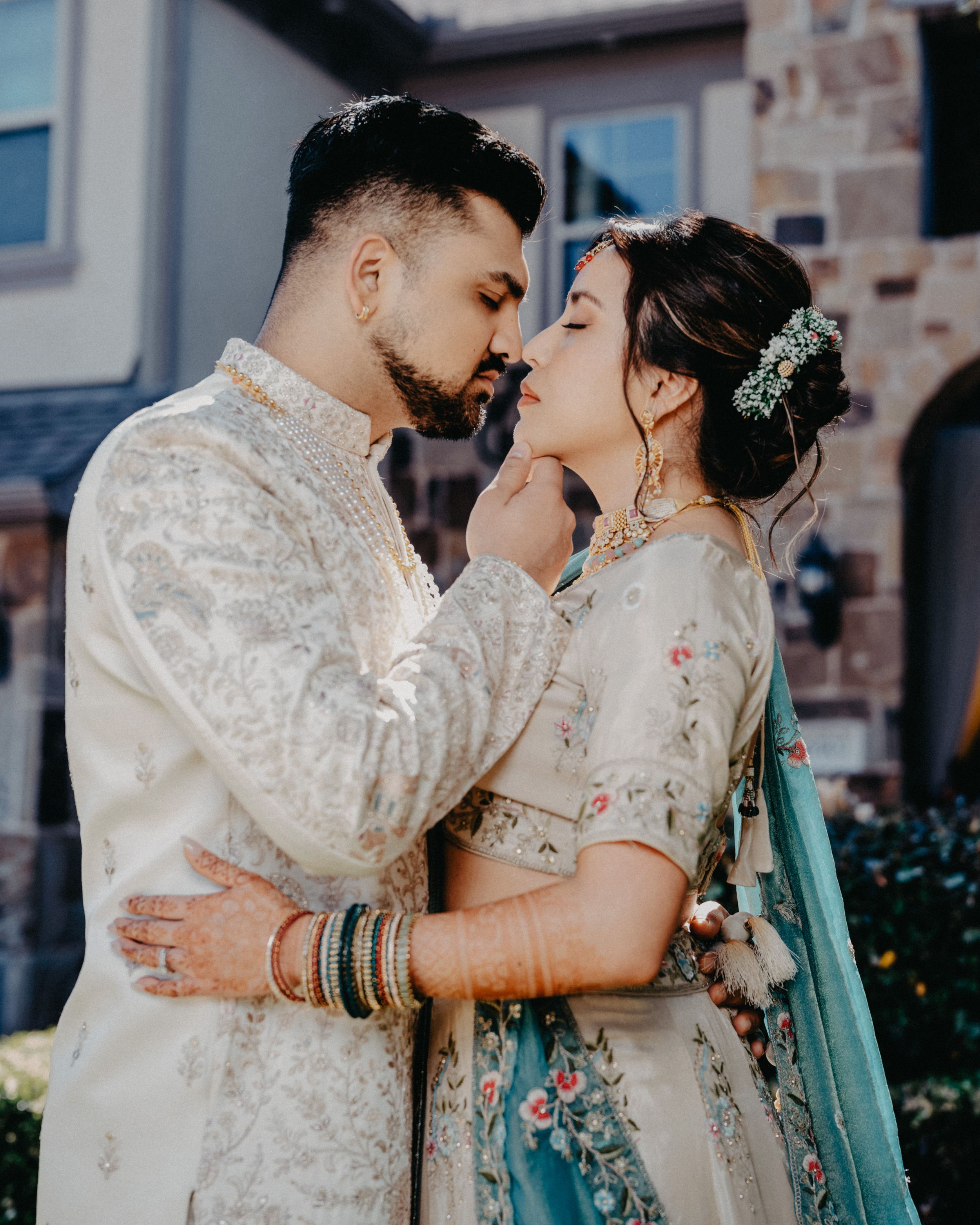A couple in traditional Indian wedding attire share an intimate moment in a series of romantic outdoor portraits.