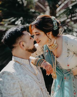 A romantic couple in traditional Indian wedding attire share tender moments in a series of outdoor photos.