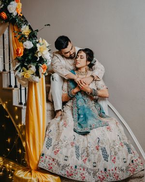A person in an ornate floral embroidered ballgown twirls gracefully in a room decorated with yellow curtains and lights.
