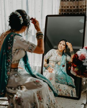 A person in a turquoise and gold traditional outfit poses in front of a mirror in a sequence of artistic shots.