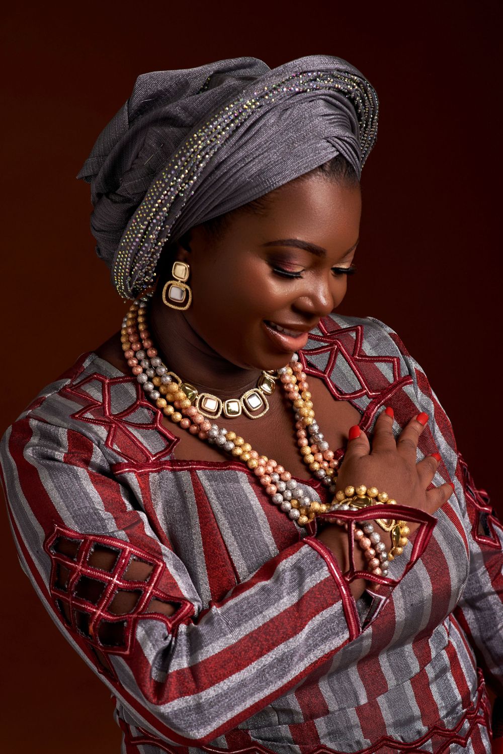 Beautiful traditional African fashion with grey and red geometric print dress, beaded headwrap and layered necklaces.
