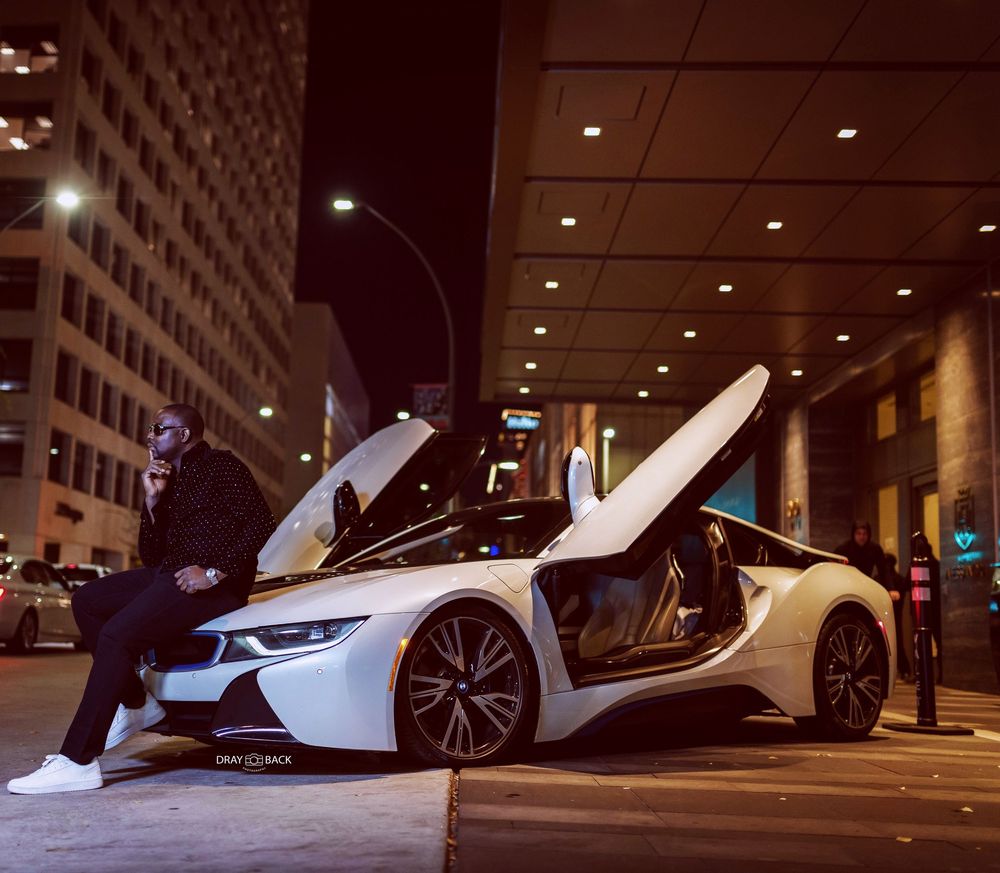 A sleek white McLaren sports car parked on a city street at night with dramatic lighting and reflections.