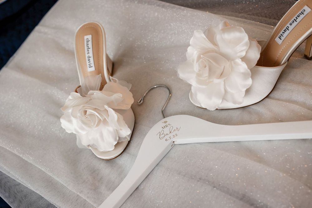 The brides high heel shows and hanger on a white bed