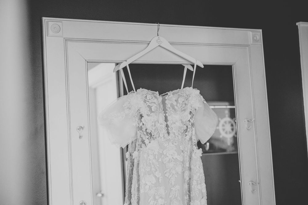 a black and white photo of the bride's dress hanging in front of a mirror