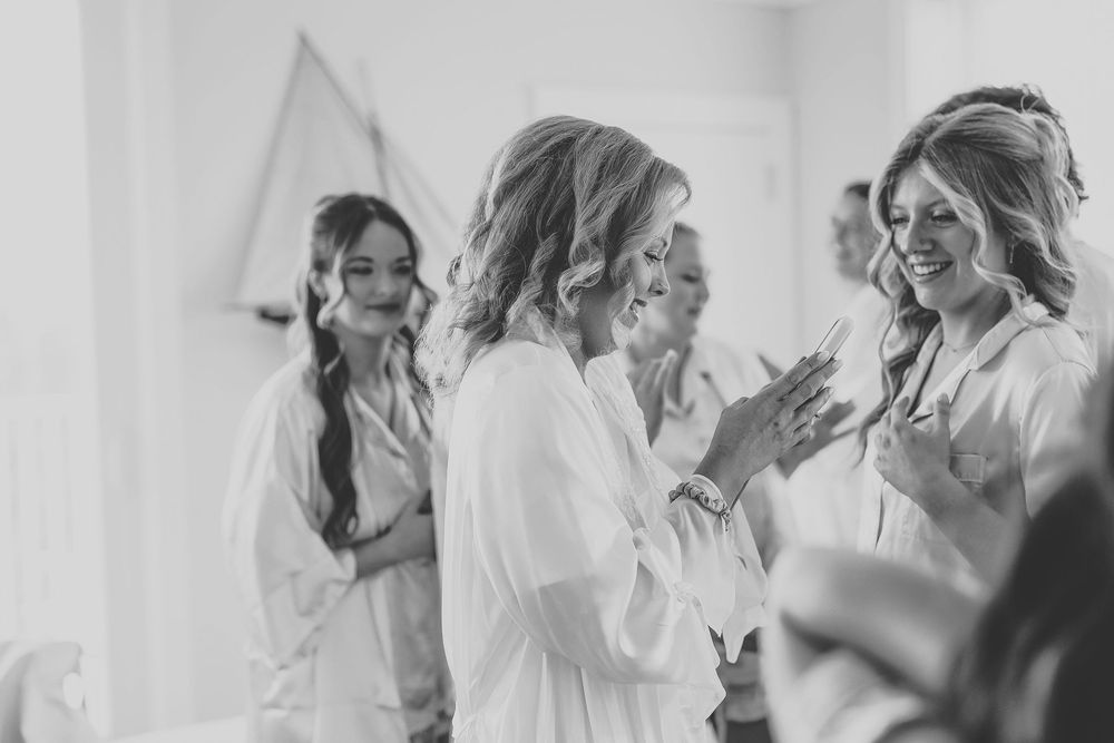 A group of bridesmaids in white robes share joyful moments together during wedding preparations.