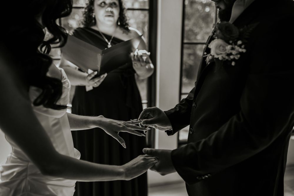 A couple in wedding attire dances together at their reception while guests watch from the background.