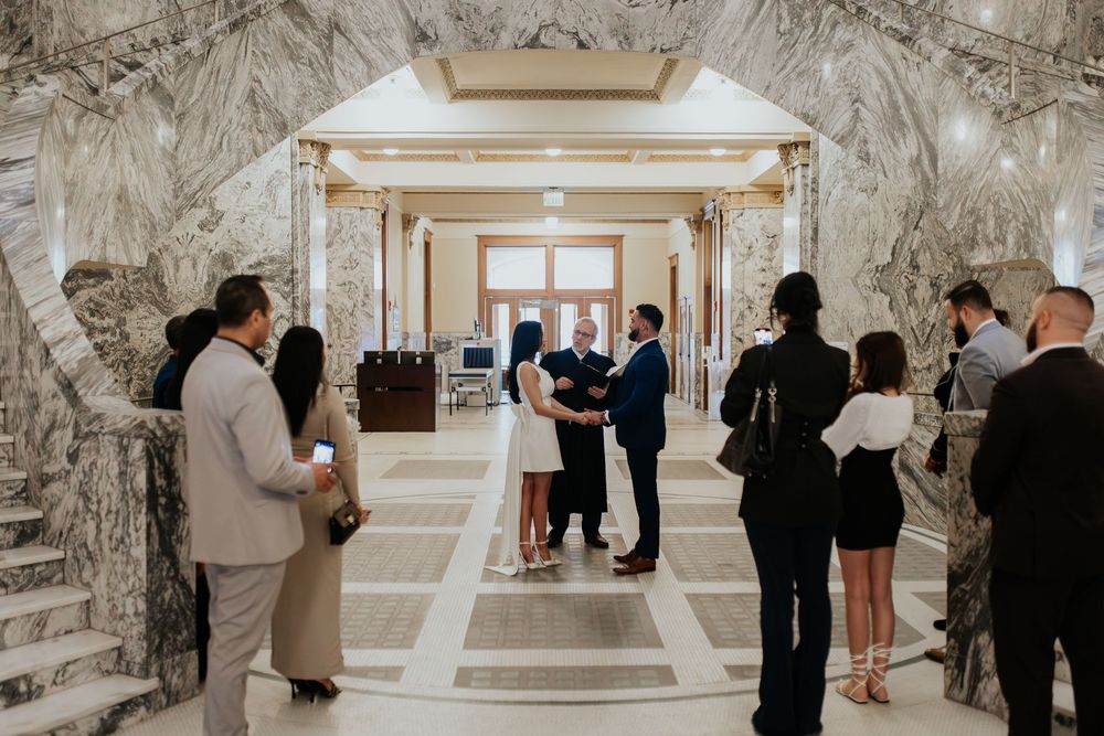 Wedding guests gather in an elegant marble-walled hallway during a formal celebration.