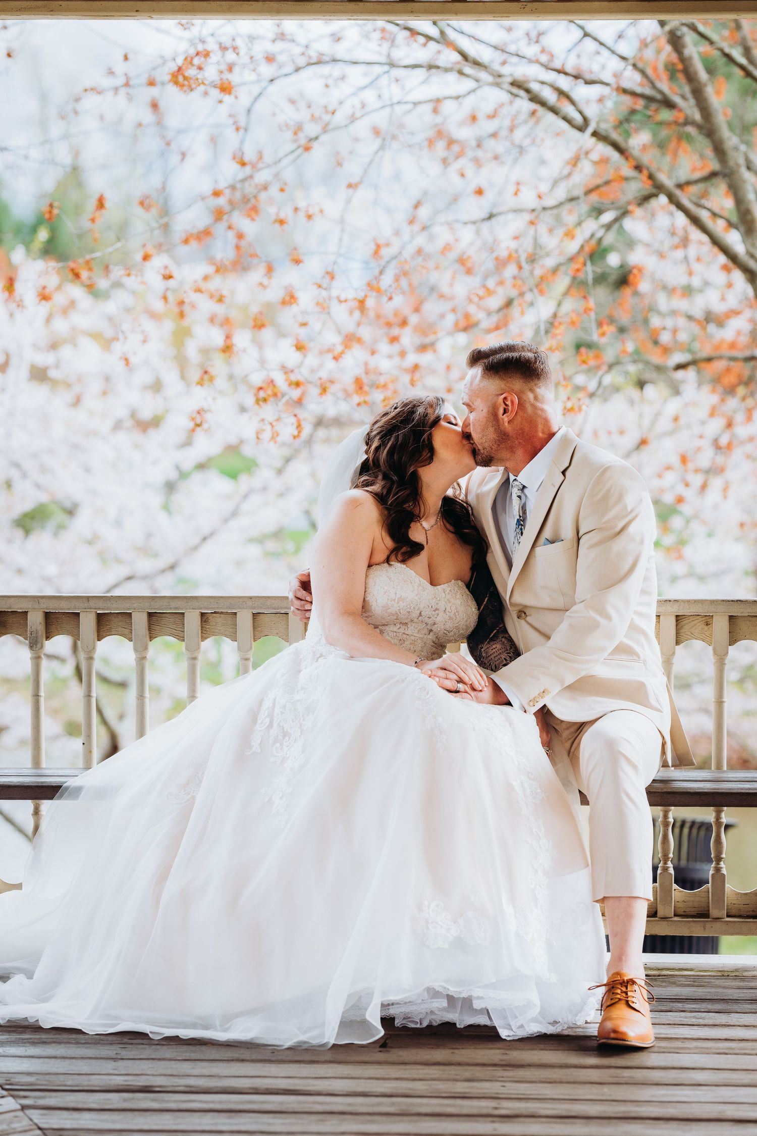 Romantic wedding couple sitting on wooden deck with autumn foliage and soft lighting in background. Annapolis videographer