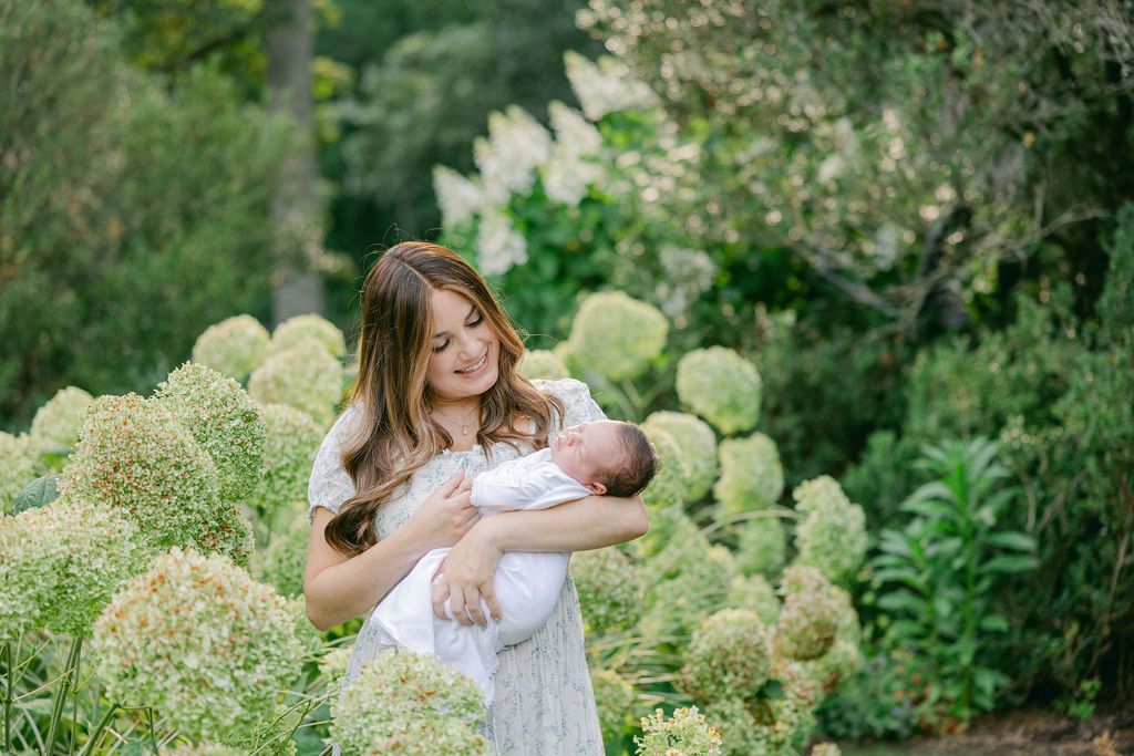 A tender moment in a garden filled with blooming hydrangea bushes on a sunny summer day. Connecticut In-home photography.