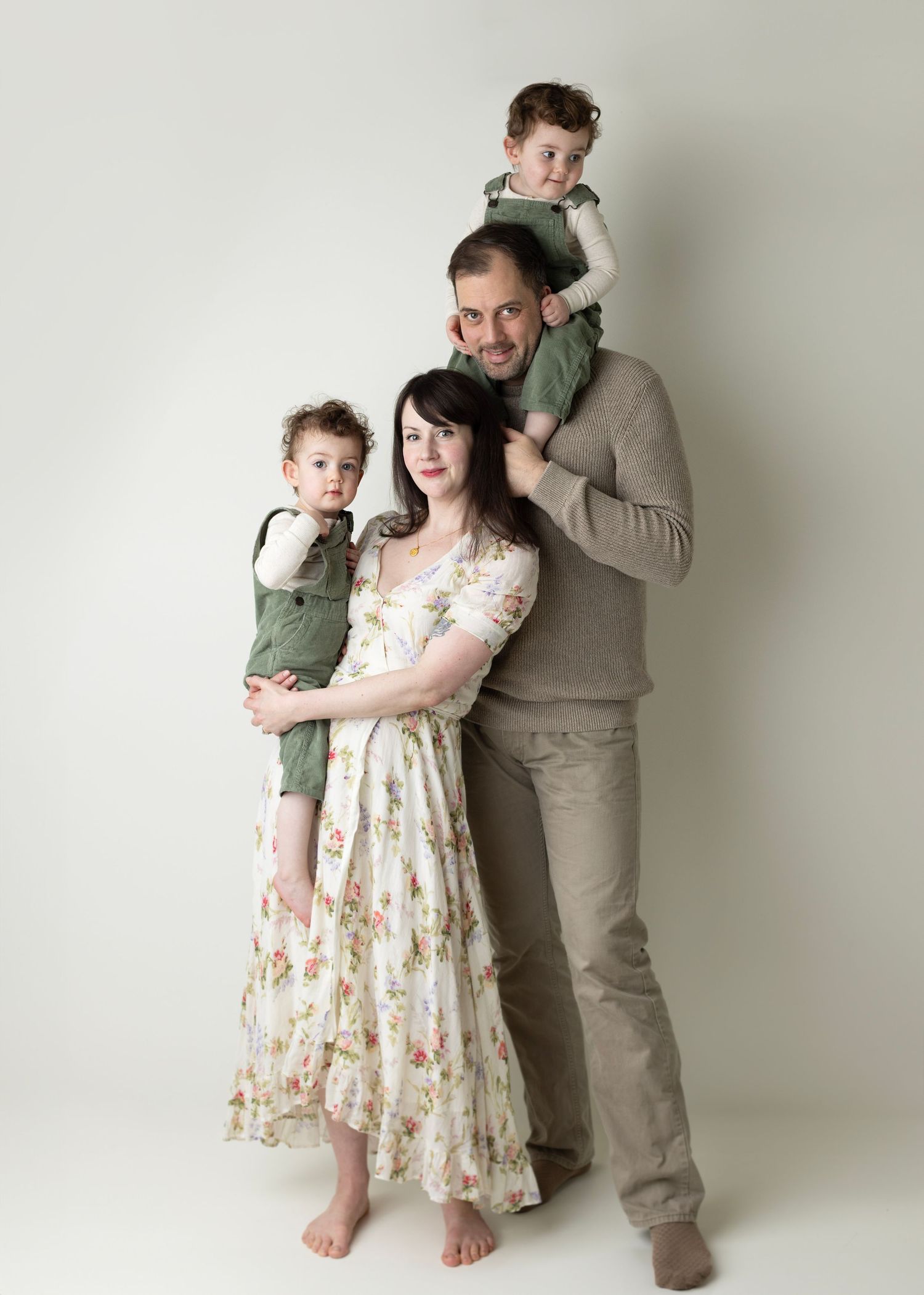 A family poses together in three casual portraits against a white backdrop wearing floral dress and olive clothing.