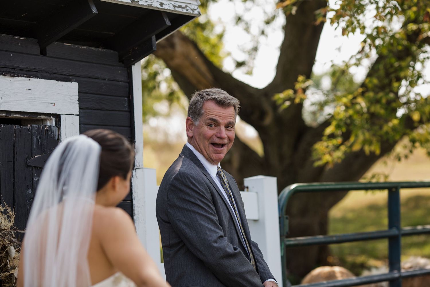 An outdoor wedding ceremony scene with white chairs and natural greenery in the background.