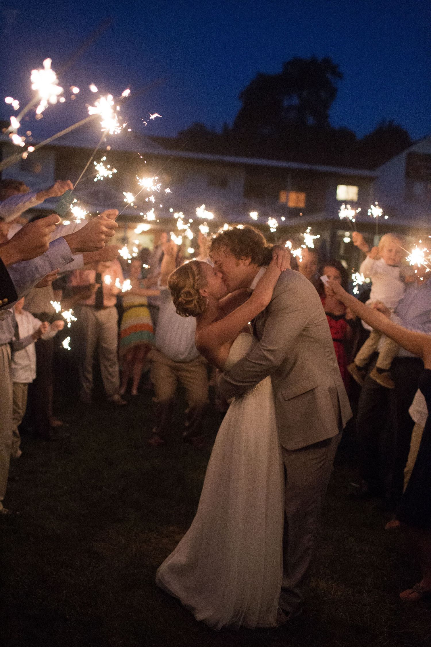 Newlyweds share a romantic sparkler-lit dance moment at their outdoor evening wedding reception.