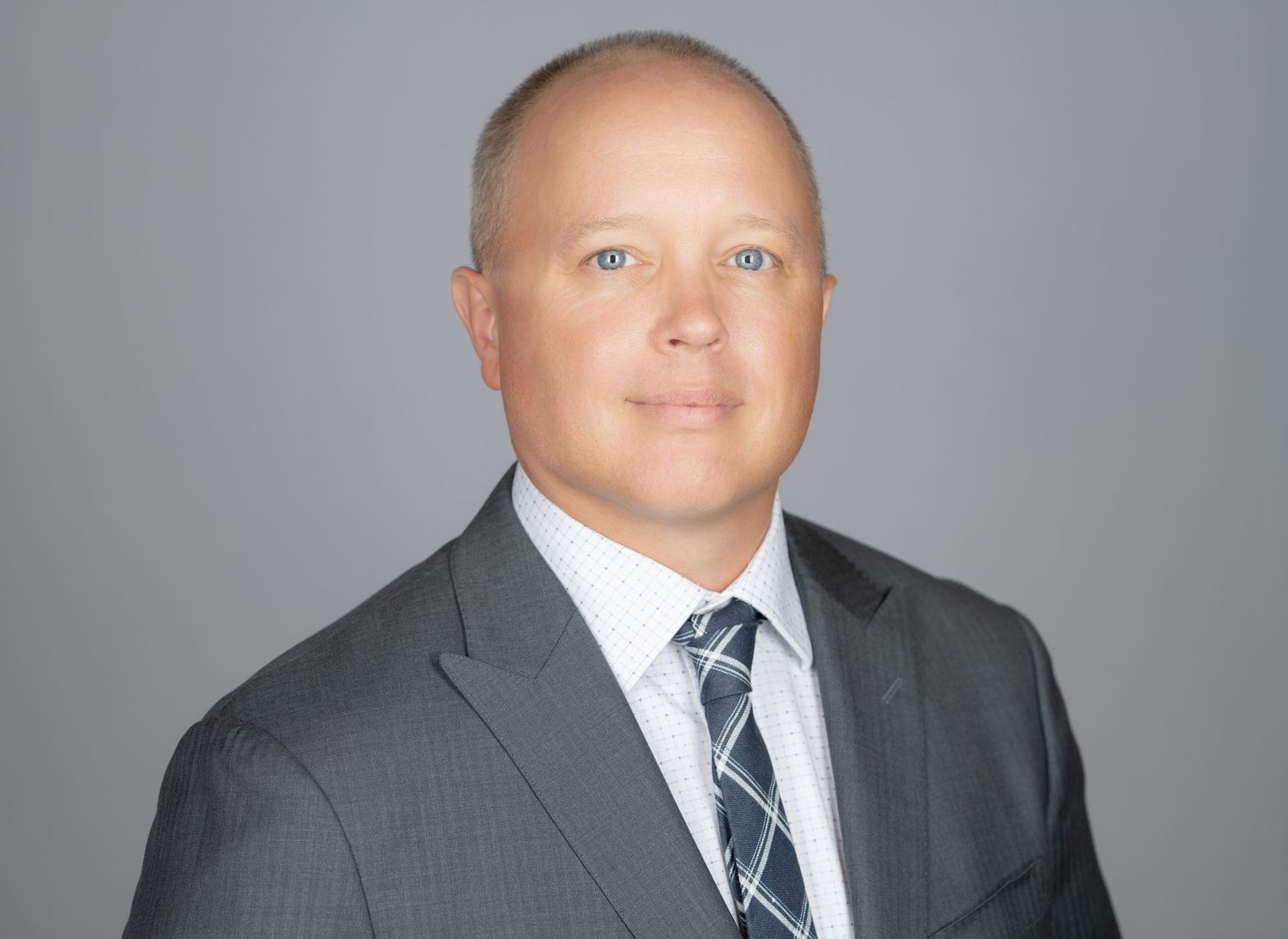 Professional headshot of person in gray suit and blue striped tie against neutral background in Summerville, SC