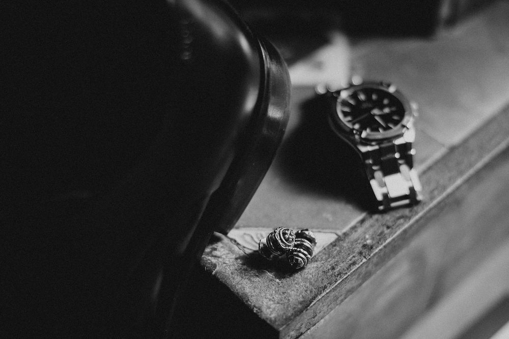 Close-up black and white photograph of a vintage wristwatch with mechanical details visible in dramatic lighting.