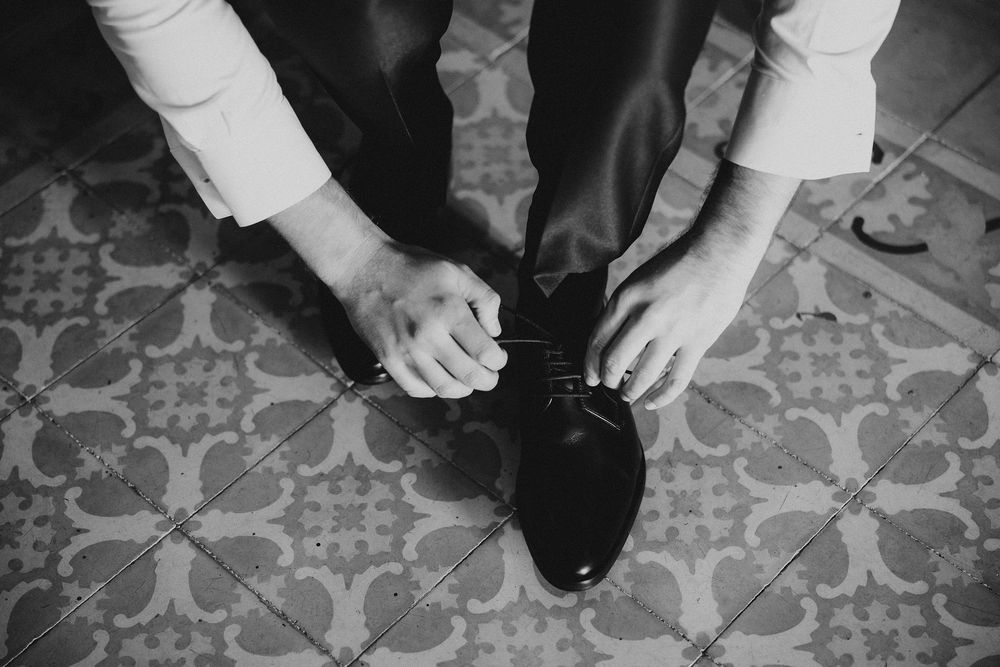 Black and white close-up shots of formal shoes and hands during wedding preparation.