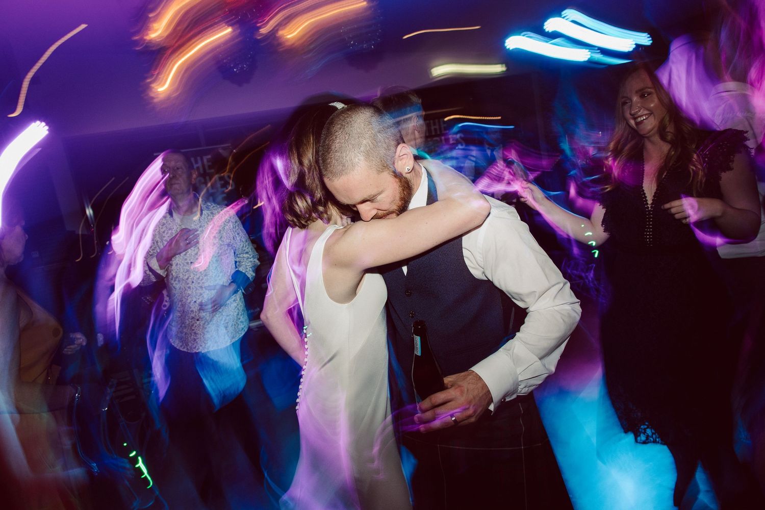 People dancing and celebrating at a lively nightclub or party with colorful lighting and energetic atmosphere.