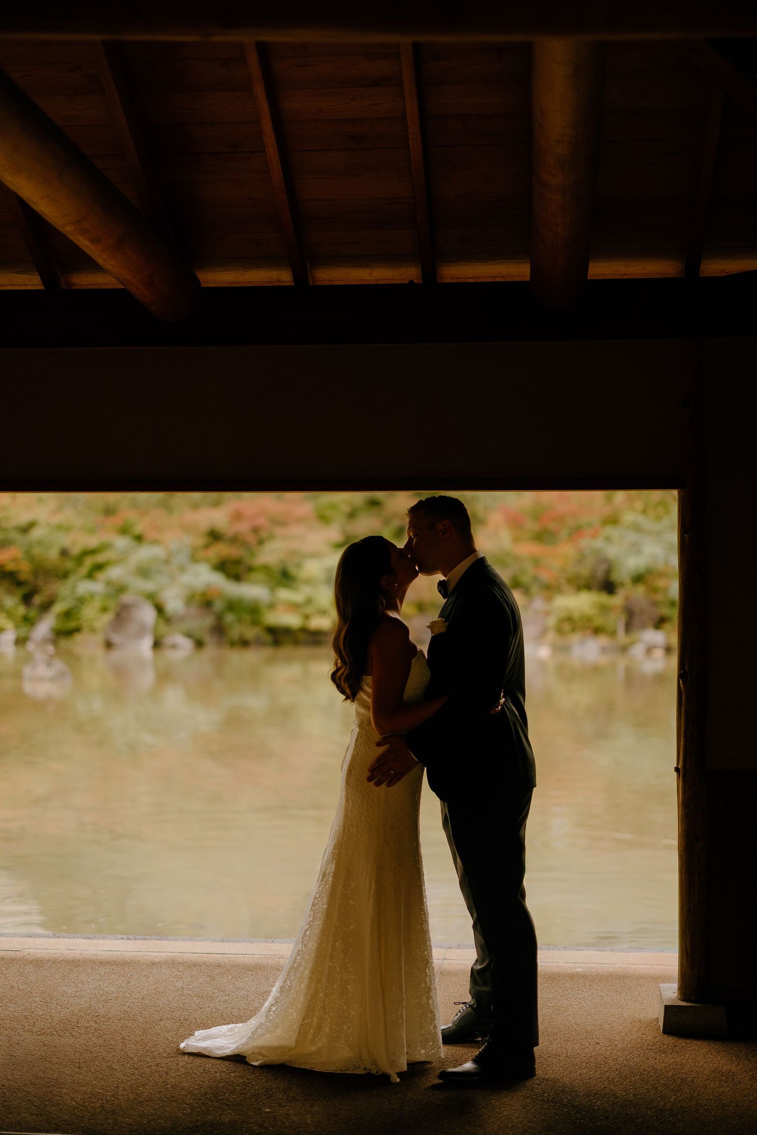 A silhouetted couple shares a romantic moment under a covered walkway during their wedding celebration.