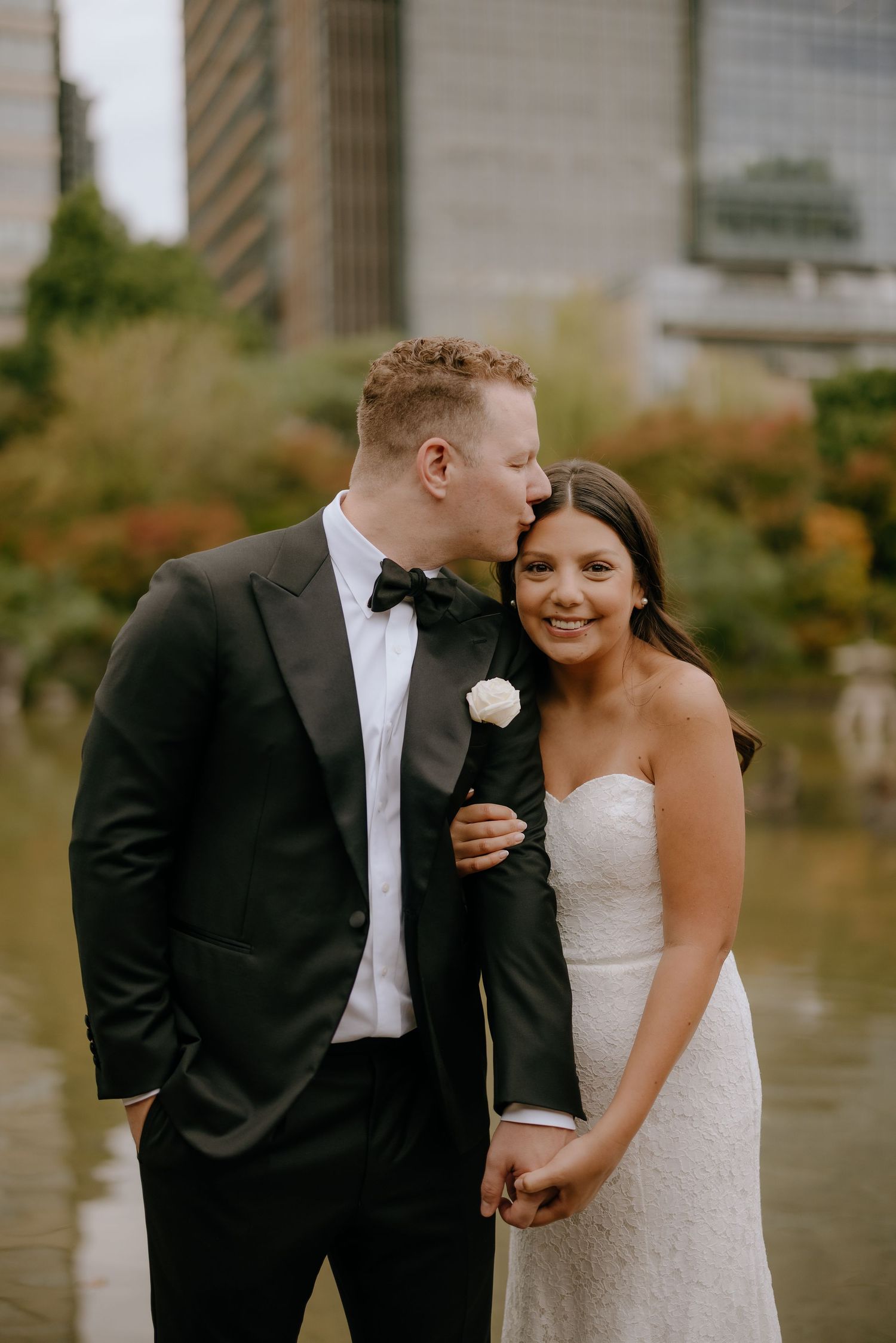 A bride and groom share intimate moments and laughter during their wedding photo session outdoors.