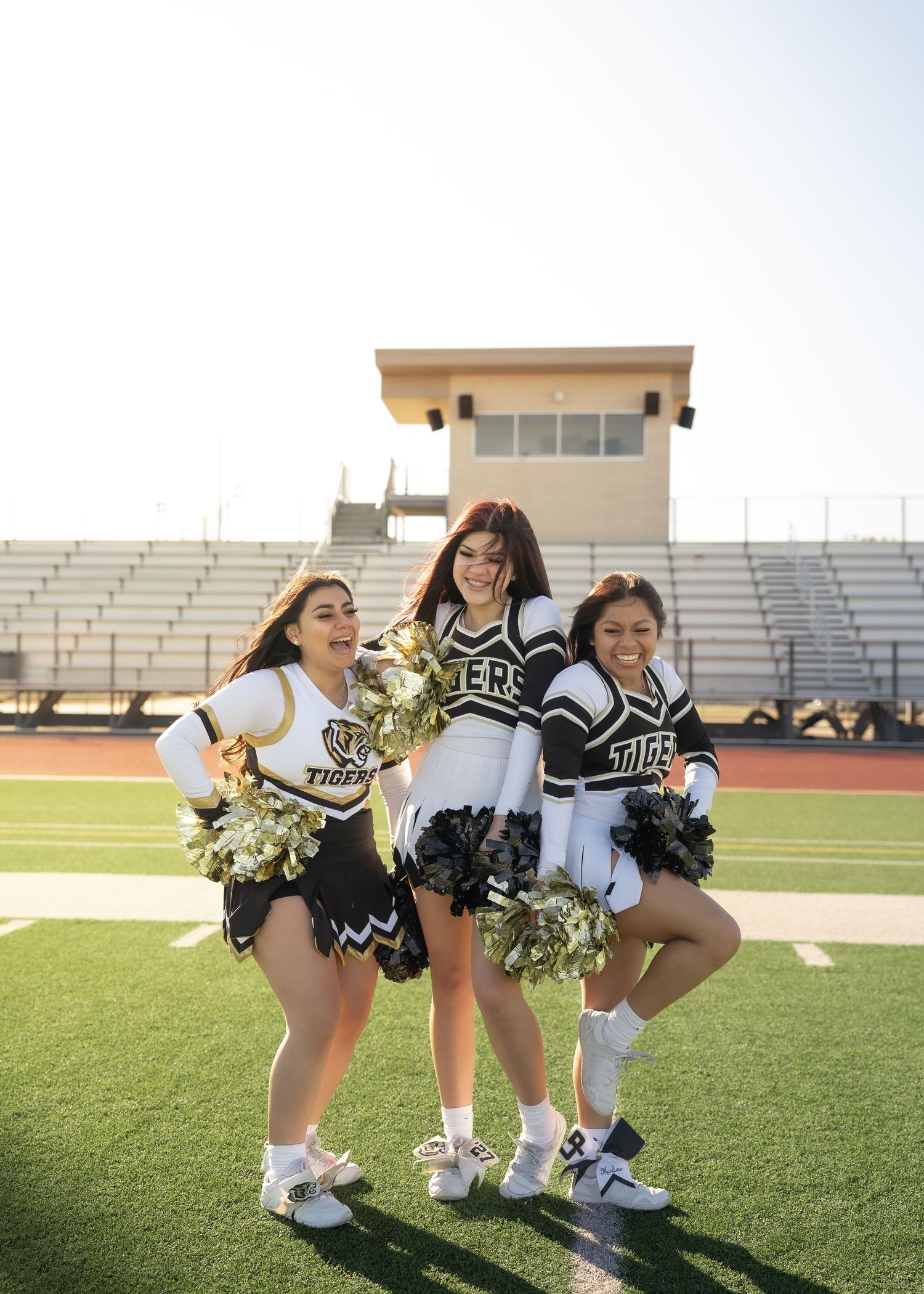 Cheerleaders tossing pom-poms in the air during outdoor group portrait