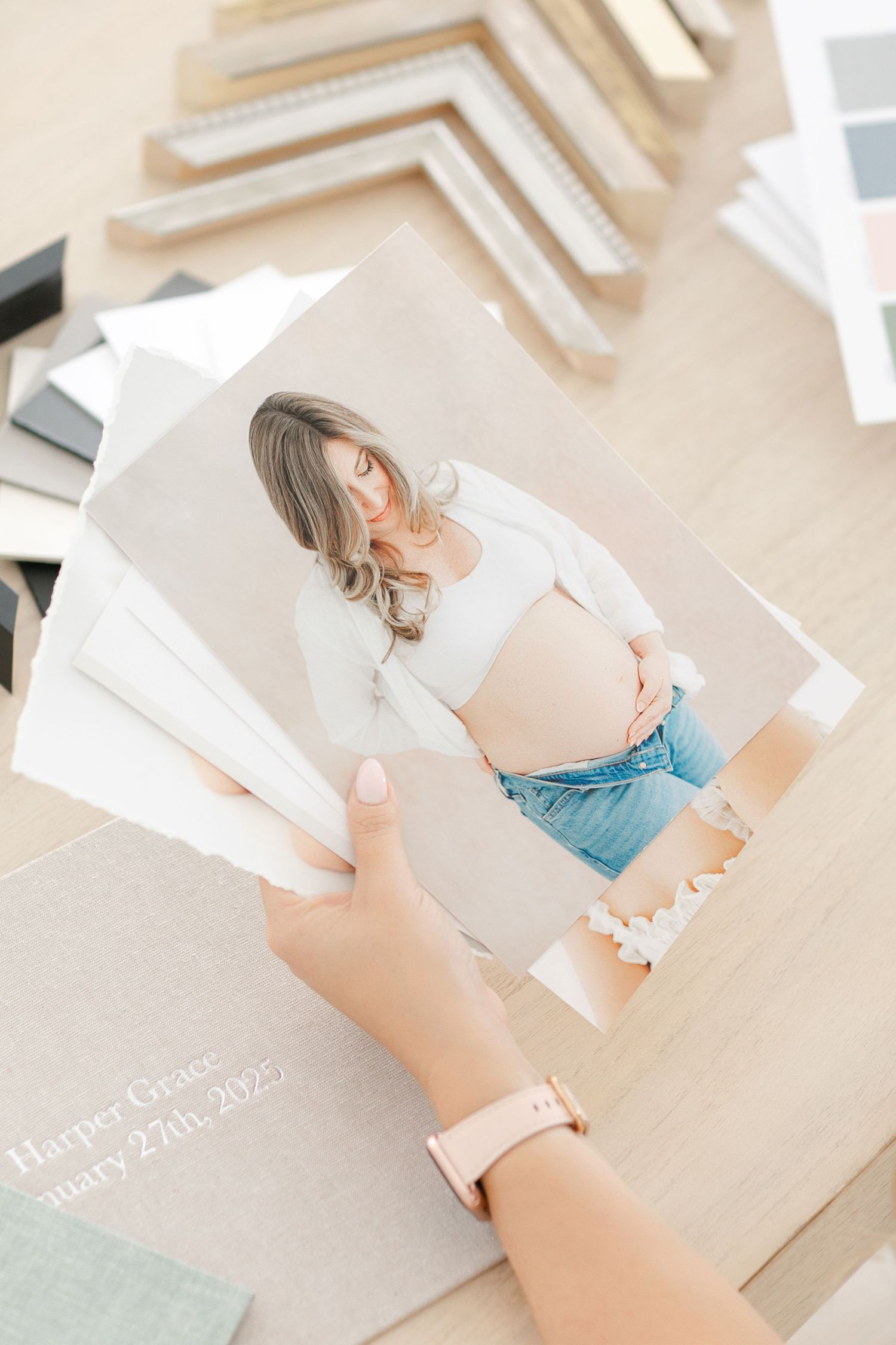 When's the best time to do a maternity shoot is answered by photographer Ashley Wilson. Here Ashley holds client print samples.