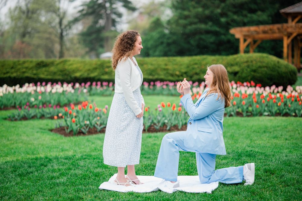 Two people in white and blue outfits sit together in a blooming tulip garden during spring.