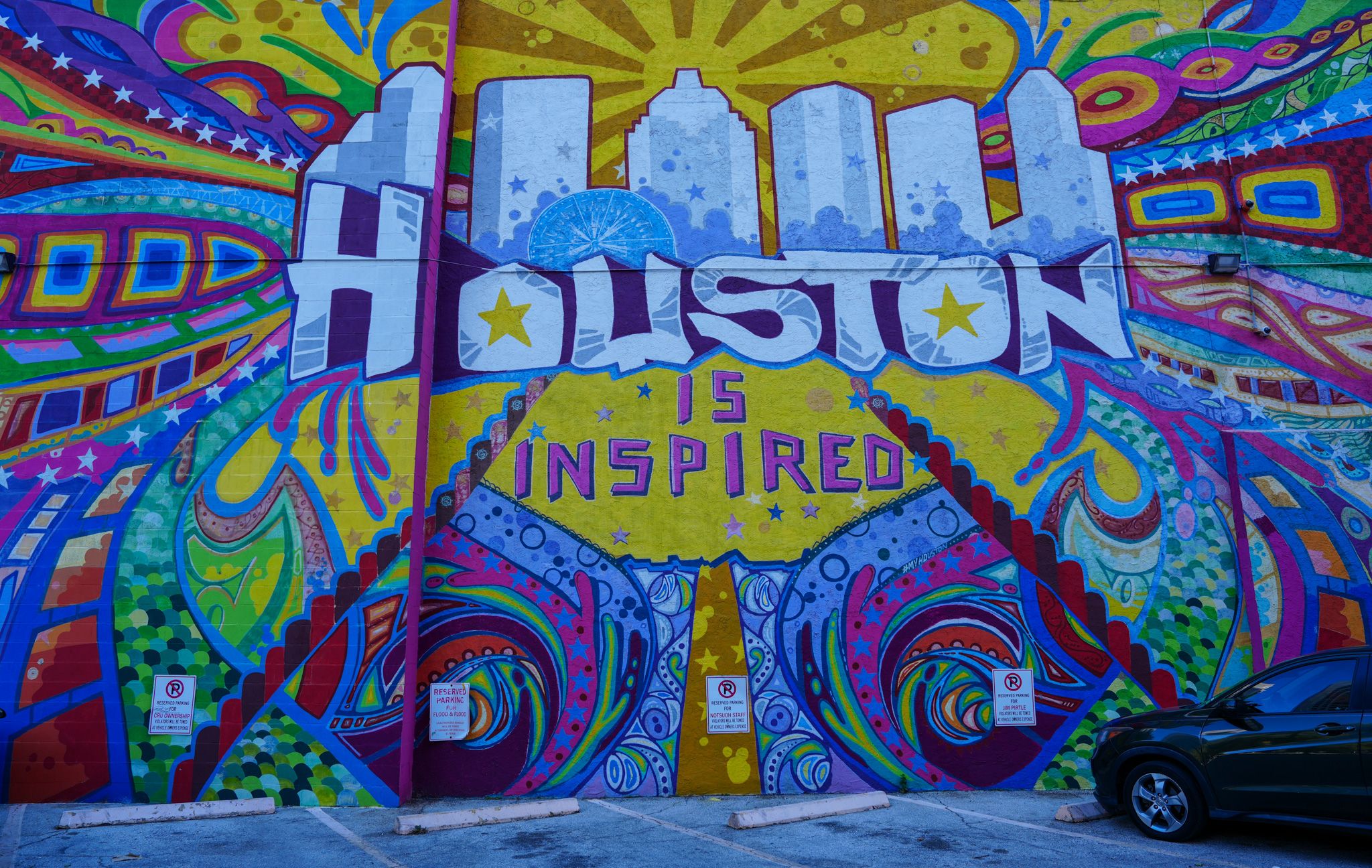 Colorful Houston Is Inspired street mural with vibrant blues, yellows, and reds on urban wall.
