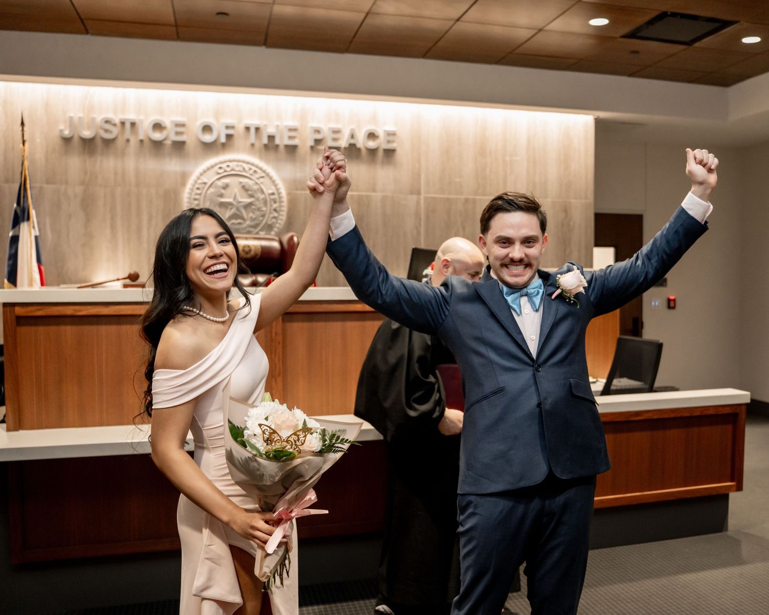 Newlyweds celebrating inside a courthouse after their civil wedding ceremony, raising their arms with joy