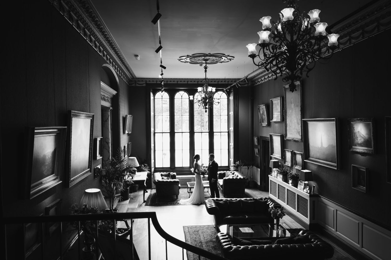 A dramatic black and white hallway interior with vintage lighting fixtures and ornate architectural details.