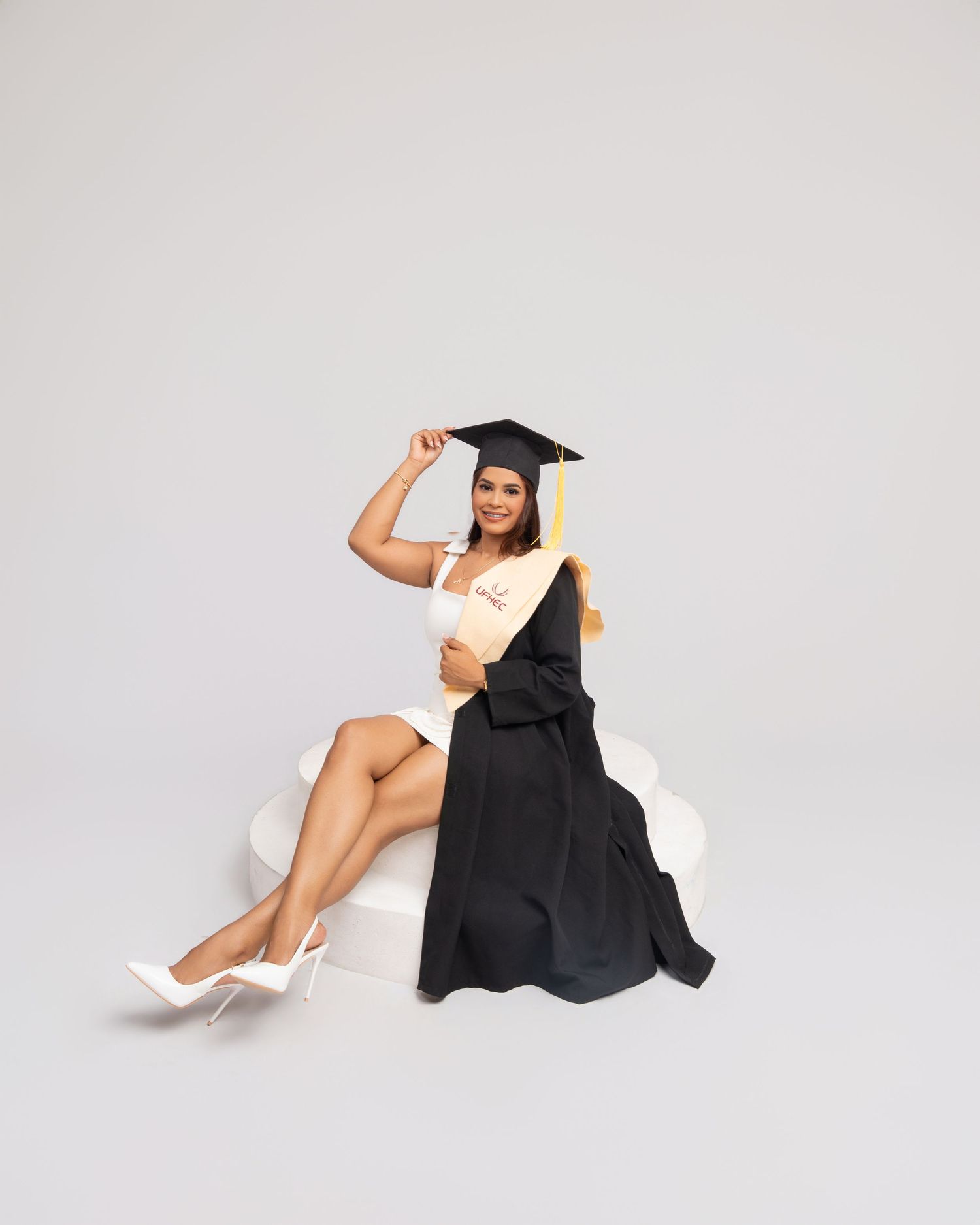 Graduate in black cap and gown holding a red diploma folder in various poses against a light background.