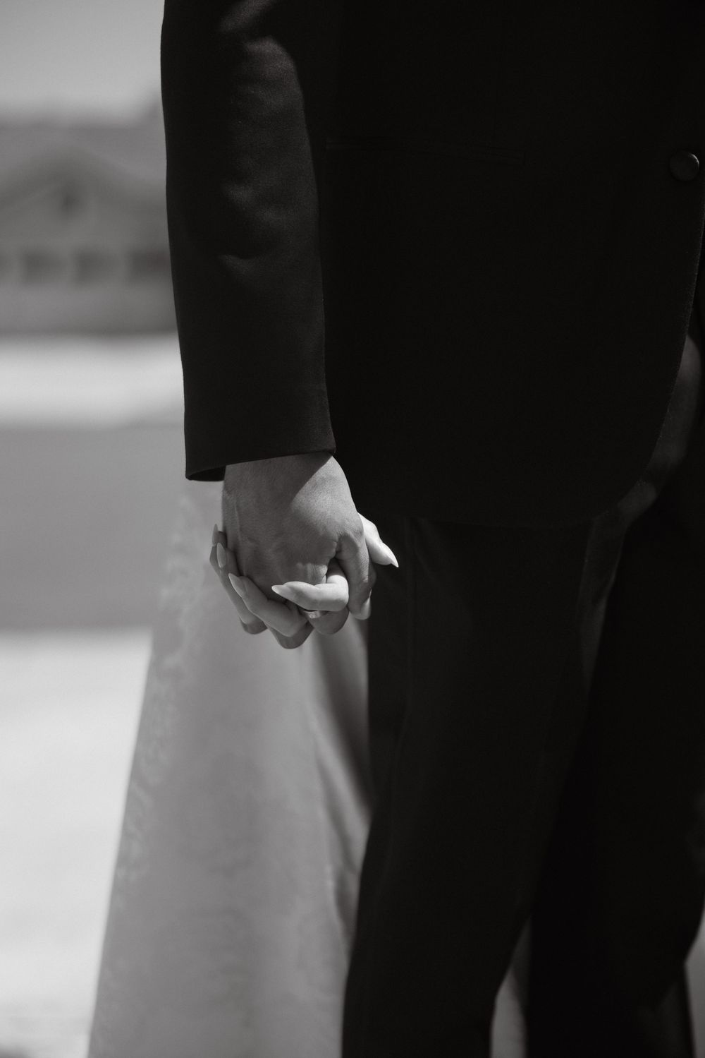 Black and white close-up of couple holding hands during a first touch before their wedding