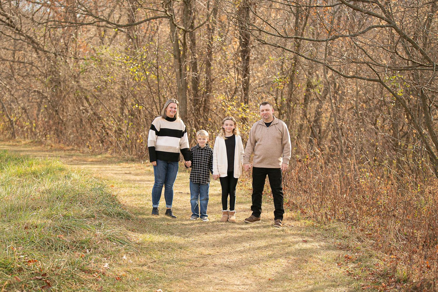 Family walking together on a nature trail surrounded by autumn trees.