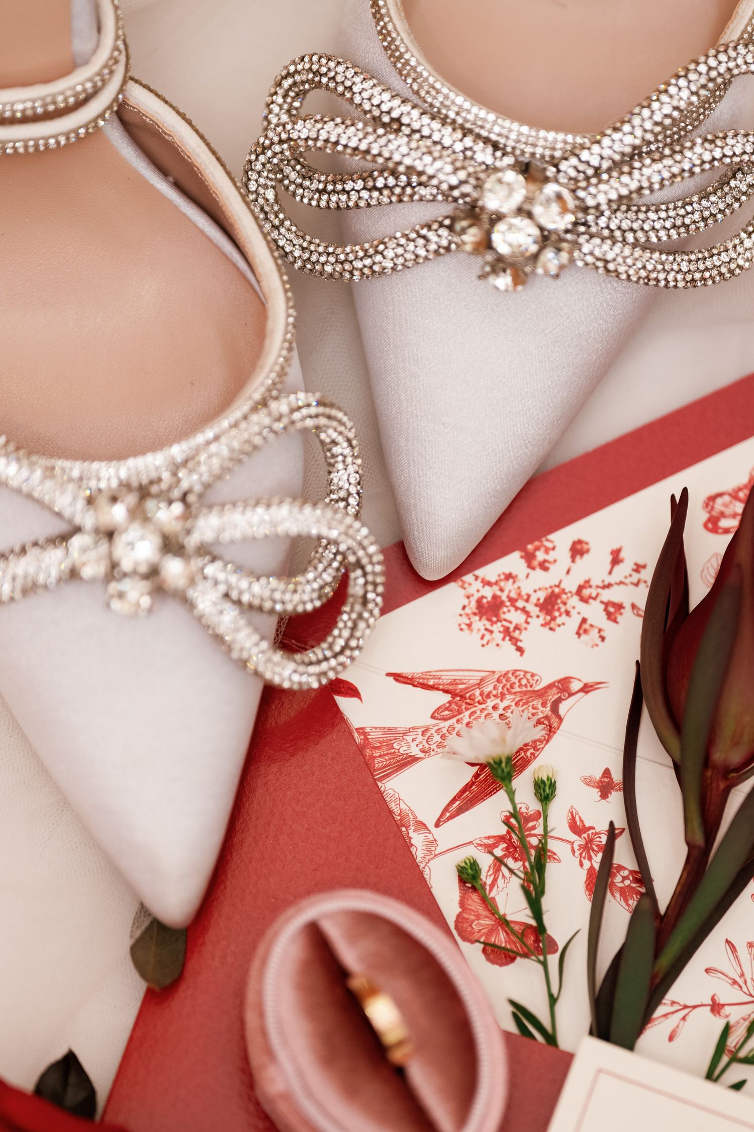 Close-up of embellished bridal shoes with pearl details and floral wedding stationery.