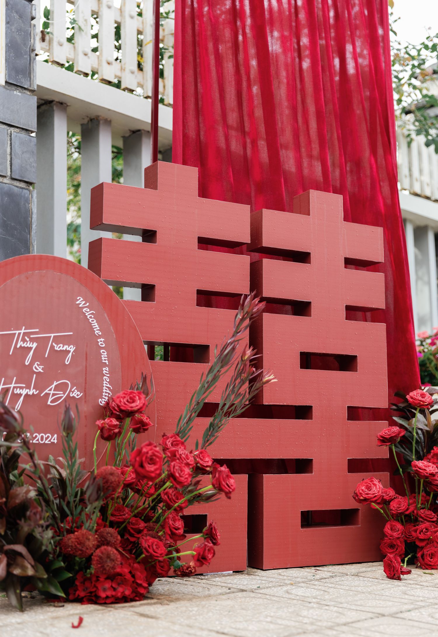 Traditional Chinese double happiness symbol in red with floral decorations and draping.