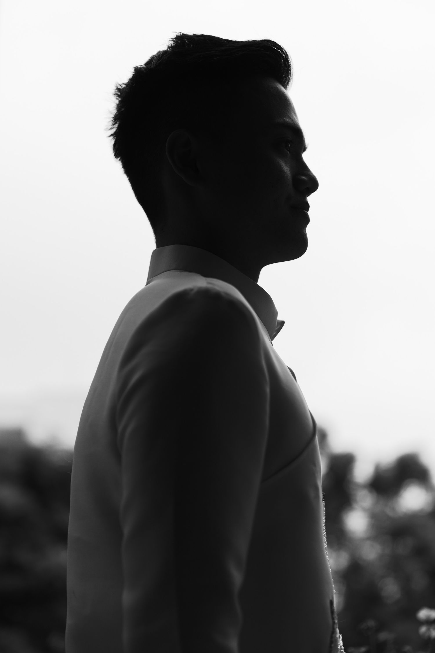 Black and white profile silhouette of person in formal attire against light background.
