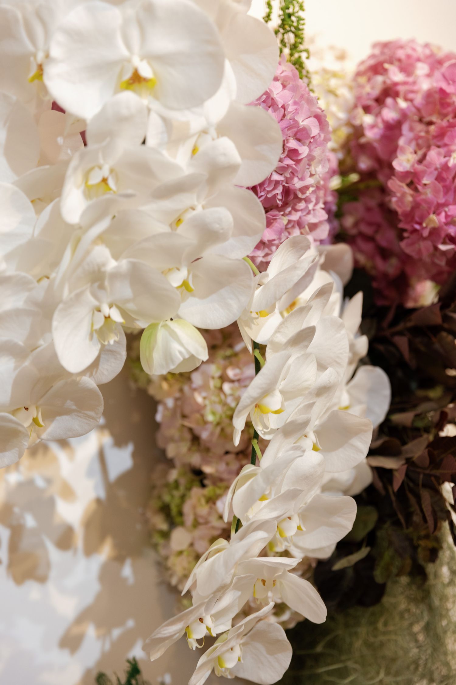 Elegant white orchids and pink hydrangeas in a luxurious floral arrangement.