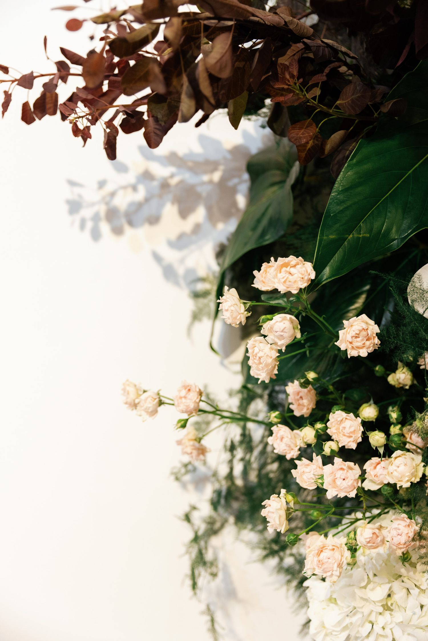 Delicate peach roses and dried brown leaves creating romantic wedding decor.