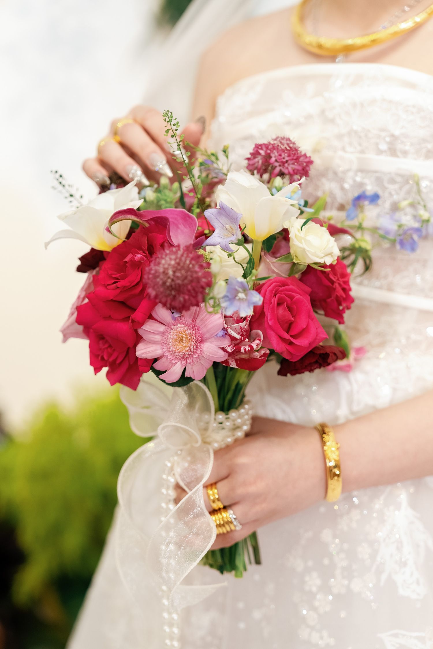 Vibrant wedding bouquet with red roses, pink gerberas and delicate blue flowers.