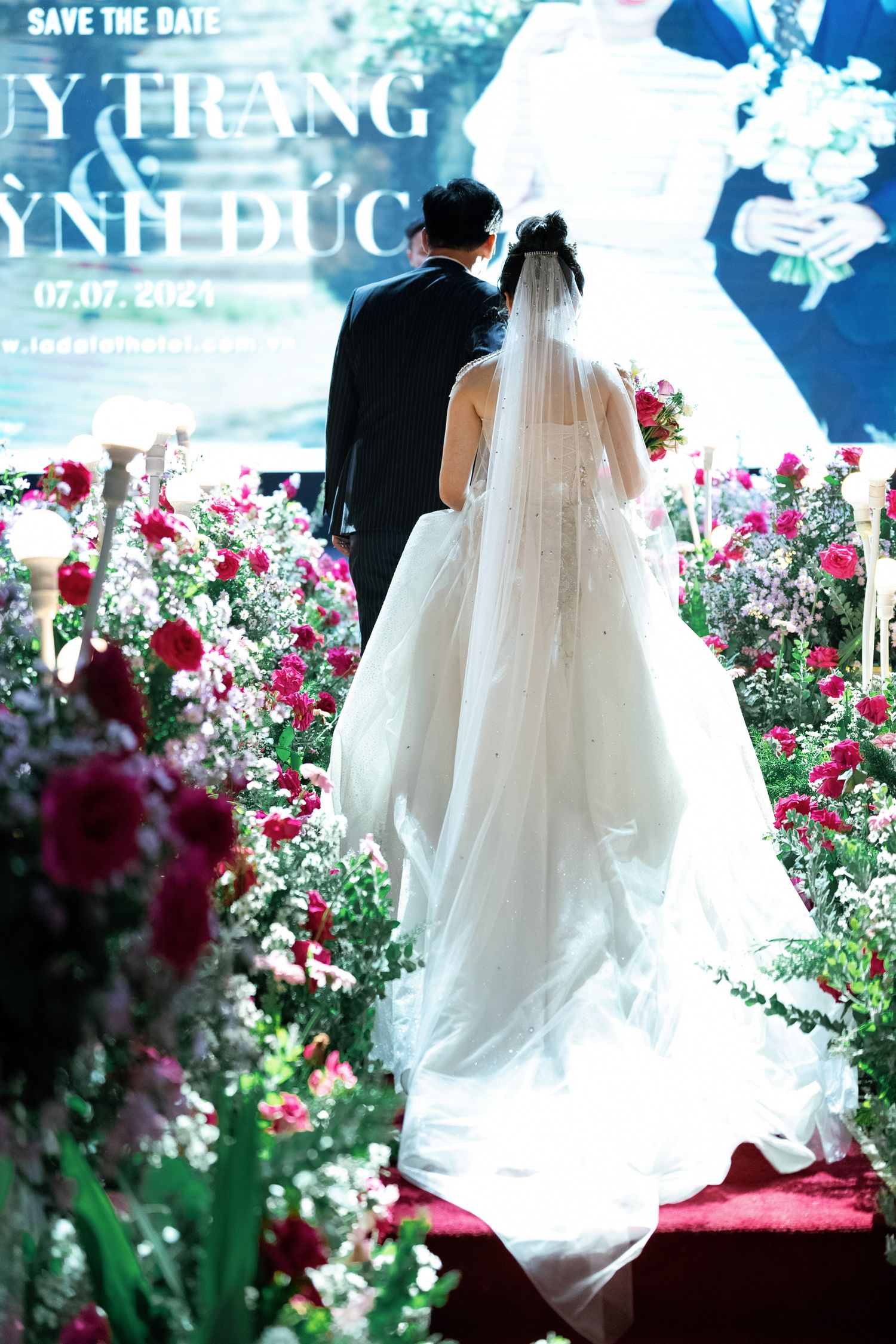 Wedding scene with floral decorations and pink roses against a blue backdrop.