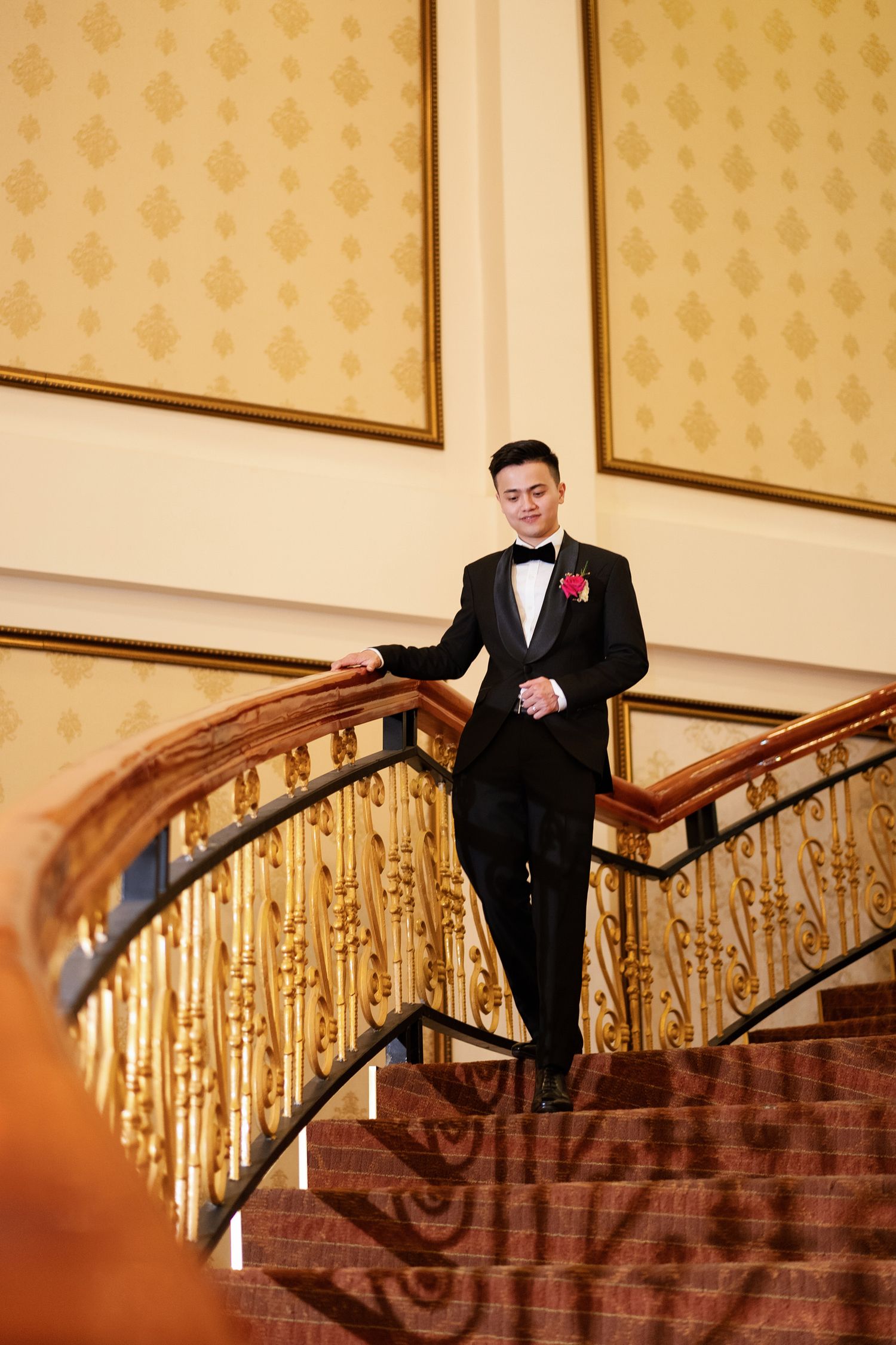 Formal event setting with elegant gold staircase and patterned wallpaper in warm tones.