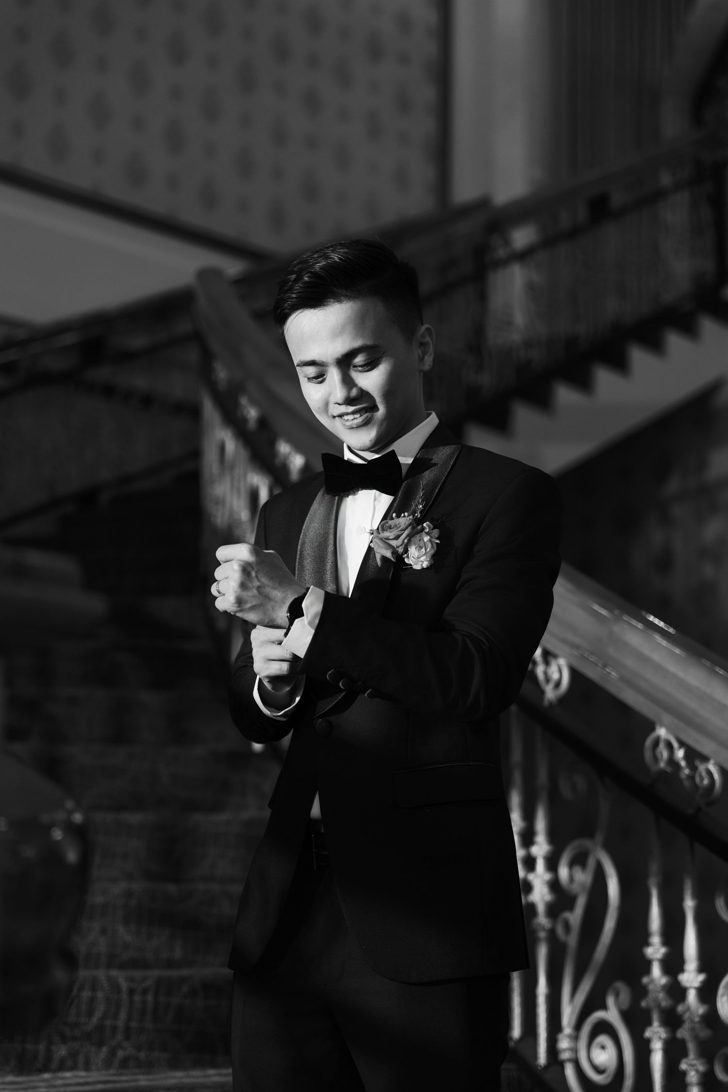 Black and white portrait on an ornate staircase with classic architectural details.