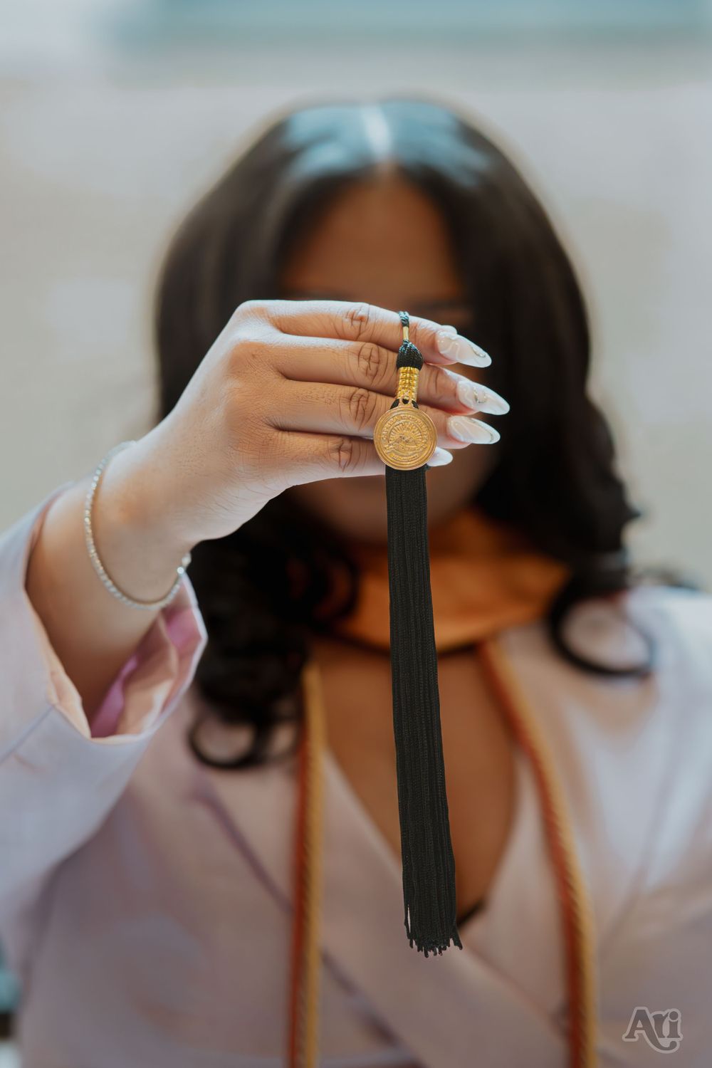 Graduate holding black tassel with gold medallion during graduation ceremony photo.